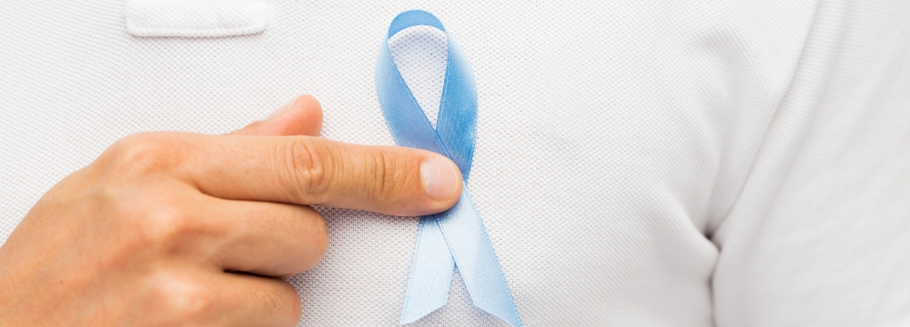 Man holding blue prostate cancer ribbon to his chest