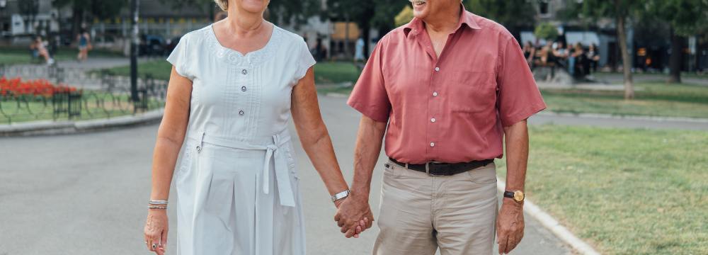 Older man and woman holding hands while walking