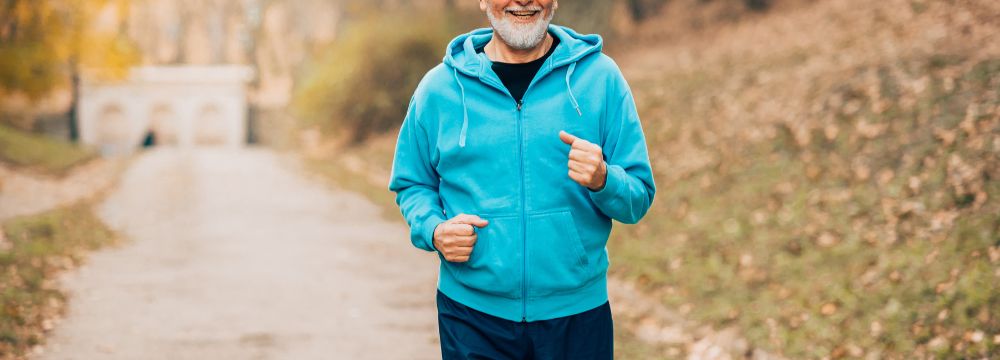 Man jogging with hoodie on trail in autumn
